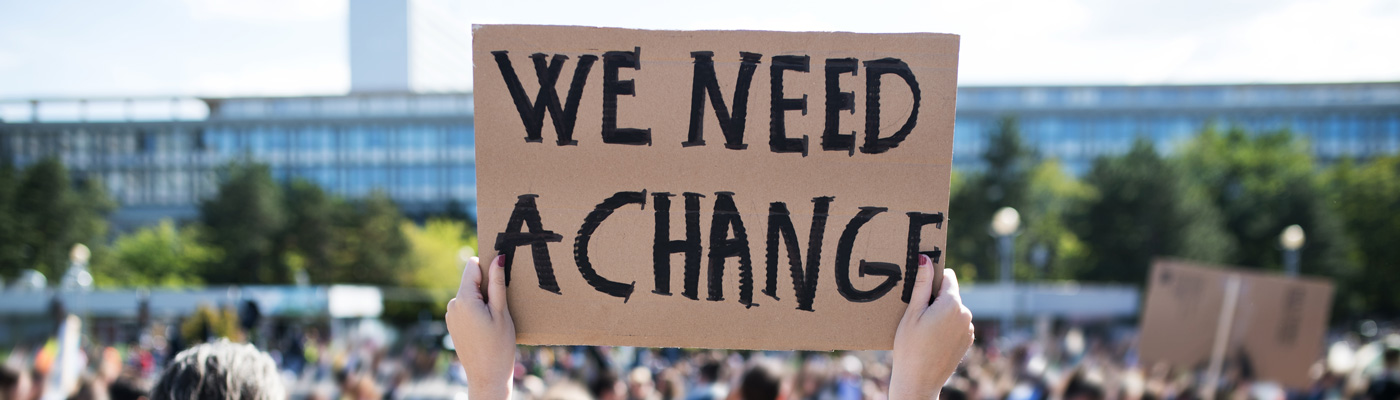 A protester brandishing a placard saying 'We need change'